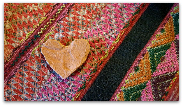 Rock in the shape of the heart on a brightly colored blanket