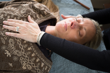 Woman with a hand laying upon her chest during a hands-on energy healing session
