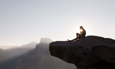 man sitting on cliff feeling the energy of holistic recovery