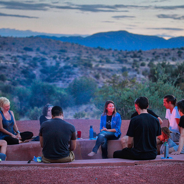 Group of residents at The Sanctuary sitting in a circle talking to each other around a fire pit