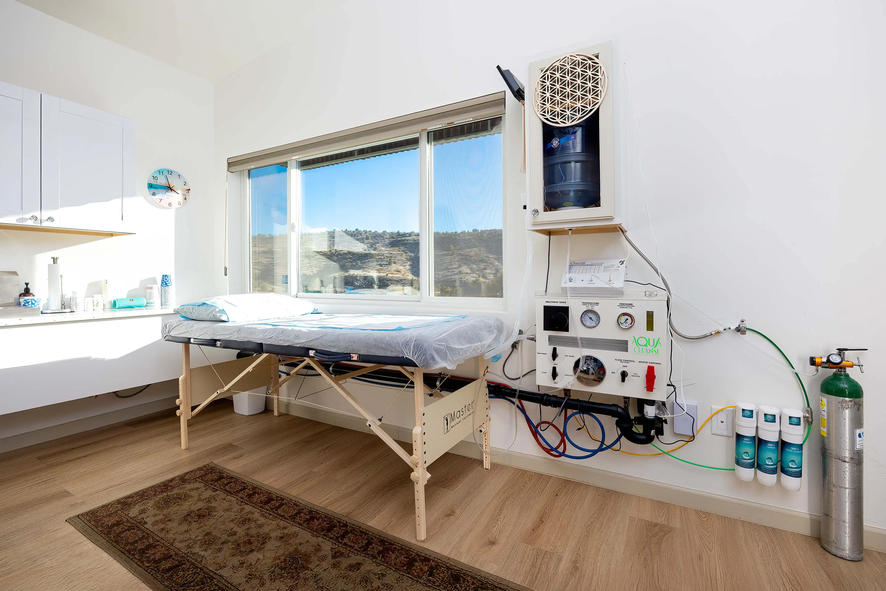 A treatment room with a massage table, medical equipment, and a window.