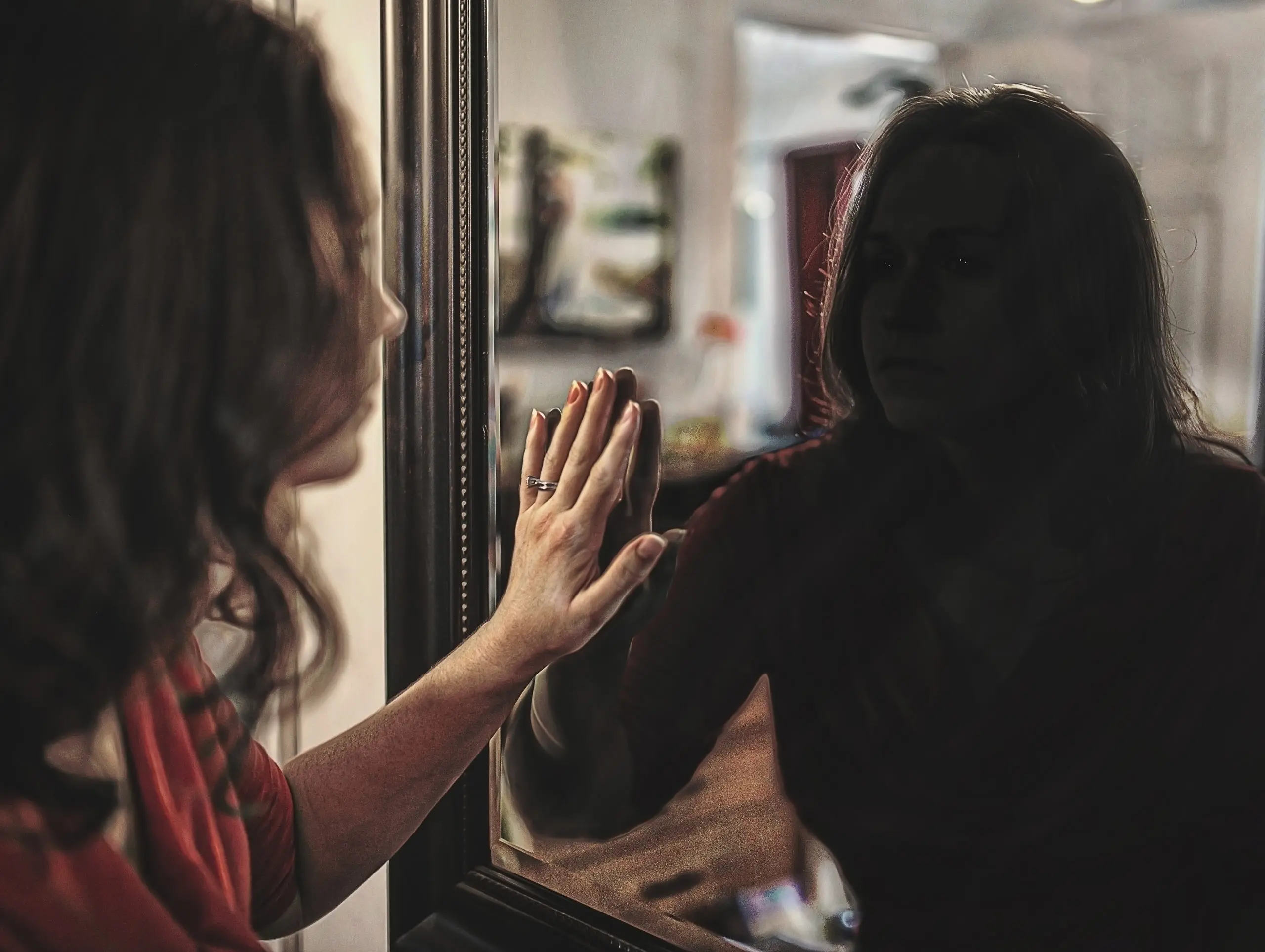 a-woman-looks-at-her-reflection-even-though-its-dimly-lit-SBI-301080950-scaled-1