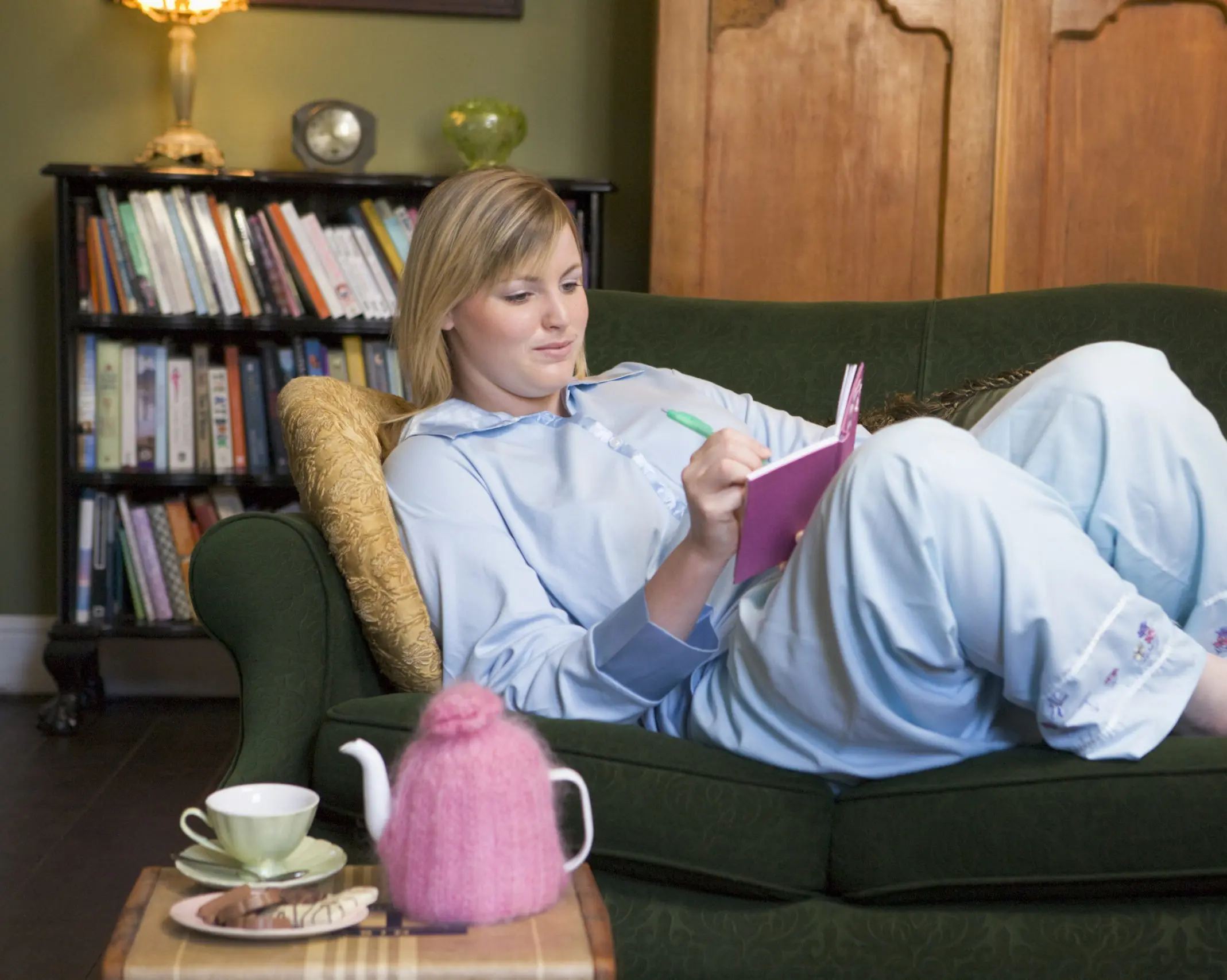 a-young-woman-lying-on-her-couch-writing-in-her-journal-SBI-301033501-scaled-e1673543873410